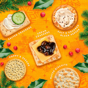 A festive flat-lay of five types of crackers arranged on a bright orange holiday-themed background with pine branches, holly leaves, and red berries. The crackers are labeled with white text: 'SALTED CRACKERS' topped with cream and a cucumber slice, 'CREAM CRACKERS' topped with cream and black pepper, 'POPPY & SESAME' topped with poppy seed cream, 'WATER BISCUITS' topped with cream, and 'SALT & CRACKED BLACK PEPPER' topped with salted cream.