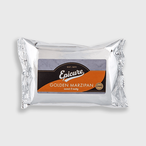 A silver foil-wrapped package of Epicure Golden Marzipan, featuring a central label with a dark brown arch, white script logo, and an orange wave design, set against a plain light gray background.