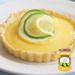 Lemon lime tart with lime slices on top and a jar of Mackay's Lime Curd.