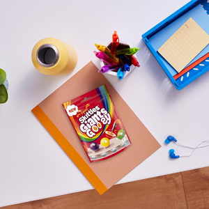 Skechers shoe box on a white surface with colorful crayons and earbuds.