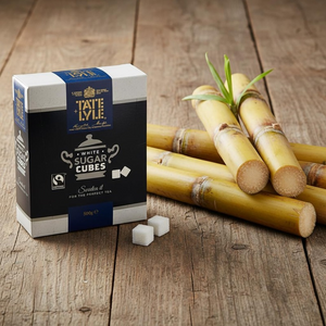 Box of Tate & Lyle white sugar cubes with sugar cane on a wooden surface