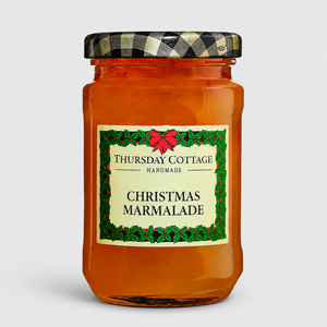 A glass jar of Thursday Cottage Christmas Marmalade with a black and white checkered lid, set against a light gray background.