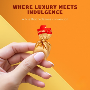 Hand holding a chocolate with red top and gold wrapper against an orange background, featuring text about luxury and indulgence.