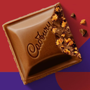Cadbury chocolate bar with a bite taken out on a red and blue background