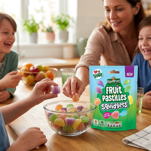 Family gathered around a table with a bowl of Fruit Pastilles Squidgers and a package of the product.