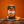 A can of Tango Orange Original soda on a wooden surface with an orange slice beside it, set against a solid orange background.