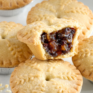 Close-up of mince pies with one cut open to reveal the filling.
