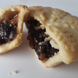 Half-eaten mince pie with fruit filling on a white background