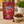 McVities Digestive Nibbles milk chocolate biscuit balls in a dark red stand-up pouch, shown on a wooden surface next to a white bowl filled with the chocolate nibbles and a few loose pieces.