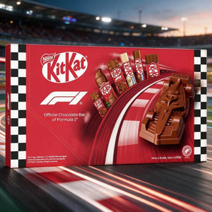 Nestlé KitKat Official Chocolate Bar of Formula 1 in a red box with racing graphics, shown on a blurred racetrack background at dusk.